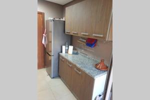 a kitchen with wooden cabinets and a refrigerator at Apartment Near & close to Casablanca Mohammed V International Airport in Nouaseur