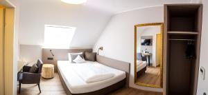 una camera d'albergo con letto e specchio di Hotel Spessartstuben a Haibach
