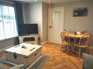 a living room with a table and a tv at Tenby Flat in Pembrokeshire
