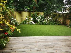a garden with a wooden walkway with flowers and a fence at Tenby Flat in Pembrokeshire