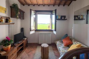 a living room with a couch and a tv and a window at La Casa di Smilla - (Bevagna) in Foligno