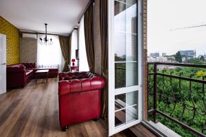 a living room with a red chair and a balcony at Abbey Road Hotel in Rostov on Don