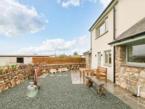a patio with wooden benches and a stone wall at Ty Gwair The Hayloft in Caernarfon
