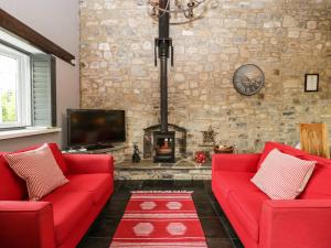 sala de estar con 2 sofás rojos y chimenea en Pear Tree Cottage, en Mark