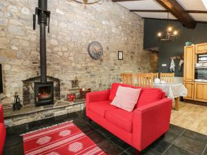 a living room with a red couch and a fireplace at Pear Tree Cottage in Mark