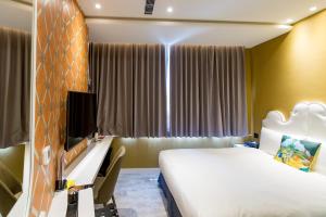 a bedroom with a bed and a desk and a television at Norway Forest Travel hotel 3 Taichung in Taichung