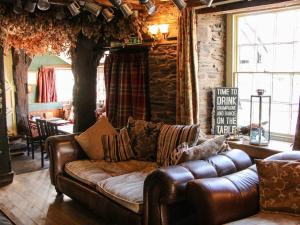 a living room with a leather couch and a table at The Boars Head Pub in Bishops Castle