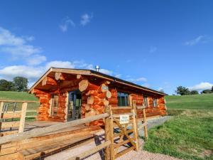 a log cabin in a field with a wooden fence at Cedar Cabin at Salford Court Farm Fishing Cabins in Worcester