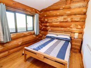 a bedroom with a bed in a log cabin at Douglas Cabin in Worcester