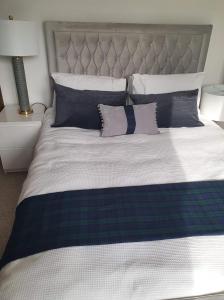uma cama grande com lençóis e almofadas azuis e brancos em Coille Darach B&B em Strontian