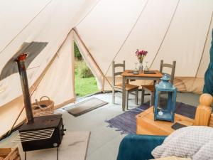a tent with a table and a stove in it at Bluebell in Hereford