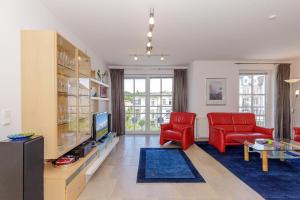 キュールングスボルンにあるHaus-Olymp-Wohnung-24-9506のリビングルーム(赤い椅子、テレビ付)