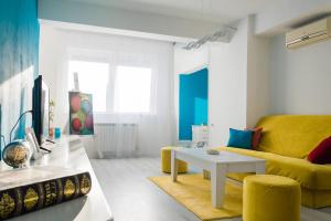 a living room with a yellow couch and a table at Aatma Apartment in Skopje
