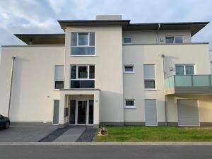a white house with a car parked in front of it at family + friends apartment ferienwohnung in Ransbach-Baumbach
