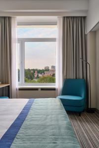 a bedroom with a bed and a blue chair and a window at Aerostar Hotel in Moscow