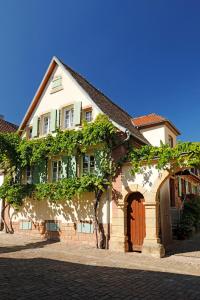 una casa con un arco y un edificio con vides en Gästehaus Zum Weinbauer, en Rhodt unter Rietburg