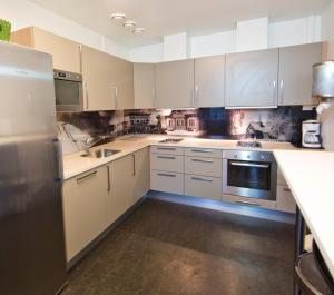 una cocina con armarios blancos y electrodomésticos de acero inoxidable en Lillehammer Stasjonen Hostel en Lillehammer