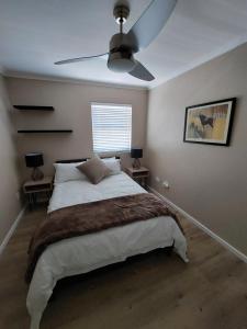 a bedroom with a bed and a ceiling fan at CherryPlum self-catering in Cape Town