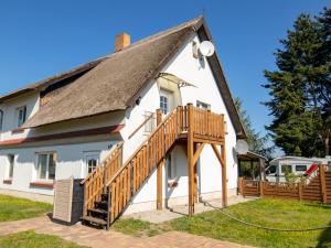 a white house with a thatched roof and a deck at Ferienwohnung Sonnenseite in Freest
