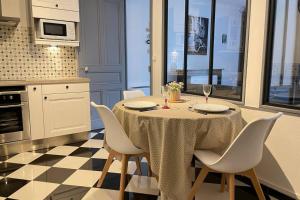 a kitchen with a table with white chairs and a kitchen with a checkered at Appartement cosy in Vannes