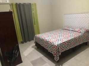 a bedroom with a bed with a red and white comforter at ApartmentsWestvillage 2bedroom in Montego Bay