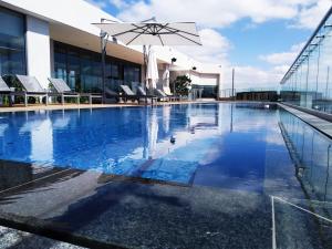 a pool with chairs and an umbrella on top of a building at Red Velvet - Lux One Bedroom in Pretoria