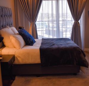 a bedroom with a bed with pillows and a window at Red Velvet - Lux One Bedroom in Pretoria