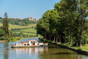 a boat on a river with a castle in the background at LA GRANGE in Saint-Prix-lès-Arnay