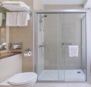 a bathroom with a glass shower with a toilet at Golden Bay Beach Hotel in Larnaca