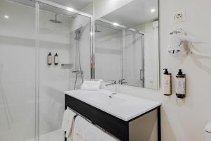 a white bathroom with a sink and a shower at Grand Luxor Village in Benidorm