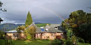 an old house with a rainbow in the background at Athanor Cottages in Hogsback
