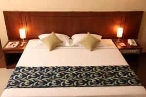 a large bed with two lamps on both sides of it at Hotel Oval in Surabaya