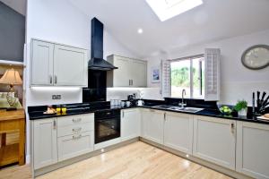 a kitchen with white cabinets and black counter tops at Oak Lodge, South View Lodges, Exeter in Exeter