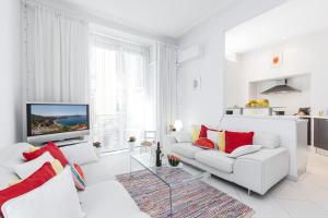 ein weißes Wohnzimmer mit einem weißen Sofa und roten Kissen in der Unterkunft FEEL HOME - GRIMALDI in Nizza