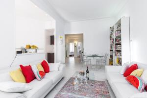 ein Wohnzimmer mit einer weißen Couch mit roten und gelben Kissen in der Unterkunft FEEL HOME - GRIMALDI in Nizza
