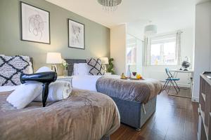 a bedroom with two beds and a table with a chair at Luxury House with Pool Table, Smart TVs, Garden and Free Parking by Yoko Property in Milton Keynes