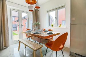 a kitchen with a table and chairs and a refrigerator at Luxury House with Pool Table, Smart TVs, Garden and Free Parking by Yoko Property in Milton Keynes