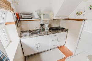 a small kitchen with a sink and a microwave at Casinha do Paiol in Porto da Cruz