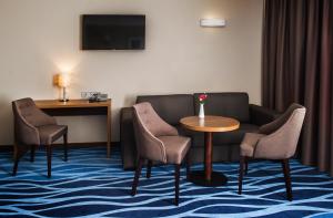 ein Hotelzimmer mit Sofa, Tisch und Stühlen in der Unterkunft Hotel Porto in Plungė