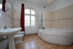 a bathroom with a tub and a toilet and a sink at Mazurski dworek przy Jeziorze in Dworackie