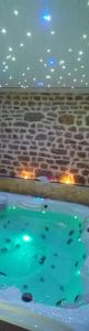 a swimming pool in a room with a stone wall at Le Ptit Spa de L'Abbaye Suite love et Spa privé in Lonlay-lʼAbbaye