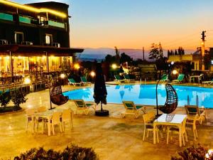a swimming pool with tables and chairs and a building at Pamukkale Whiteheaven Suite Hotel in Pamukkale