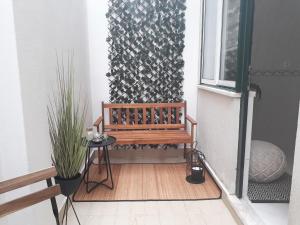 un banc en bois assis sur un porche à côté d'une fenêtre dans l'établissement Apartamento nas Olaias a 5 minutos da Faculdade ISEL e IST, à Lisbonne 5 autres photos