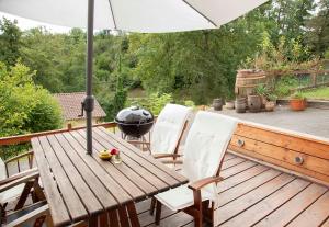 una mesa de madera y sillas con una sombrilla en la terraza en L'IDYLLIQUE - Studio Privé Sous Maison - BY PRIMO C0NCIERGERIE en Saint-Didier-sur-Beaujeu