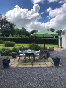 a table and chairs with a green umbrella at New Thatch Farm, knocklong, Limerick in Cross of the Tree