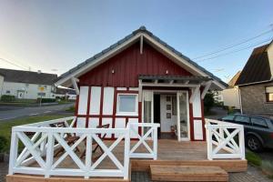 ein rotes und weißes Haus mit einer Holzterrasse in der Unterkunft Ferienhaus im Westerwald Westerwälder Herzstück in Langenbach bei Kirburg