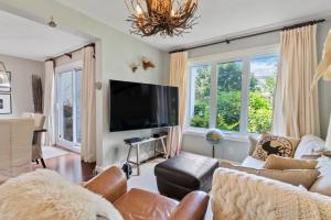 een woonkamer met een bank en een flatscreen-tv bij Elegant Sierra Lane Retreat 88780 in Blue Mountains