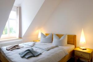 ein Schlafzimmer mit einem Bett mit weißer Bettwäsche und zwei Lampen in der Unterkunft Ferienwohnung Mohnblume in Pülzig