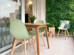 een houten tafel met twee groene stoelen en een tafel bij Precioso y acogedor apto con ubicación inmejorable in Alicante