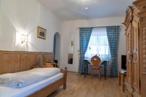 a bedroom with a bed and a desk and a window at Fischerstüberl Attel in Wasserburg am Inn